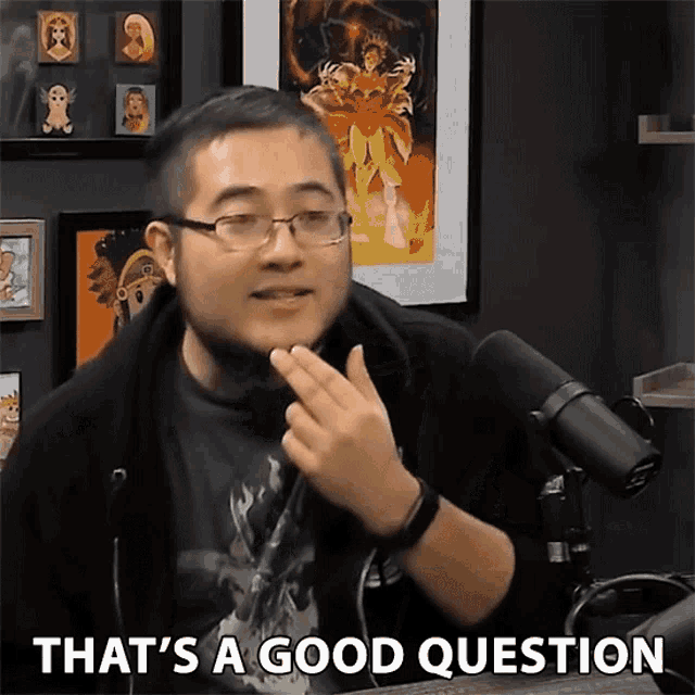 a man with glasses says that 's a good question in front of a microphone