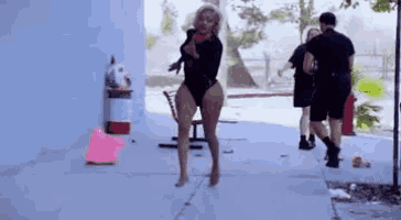 a woman in a bathing suit is walking down a sidewalk while holding a baby .