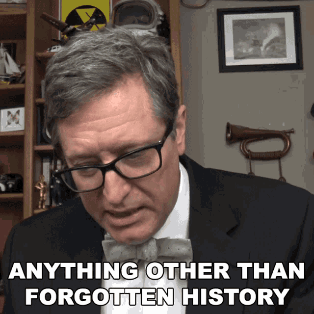 a man wearing glasses and a bow tie has the words anything other than forgotten history above his head