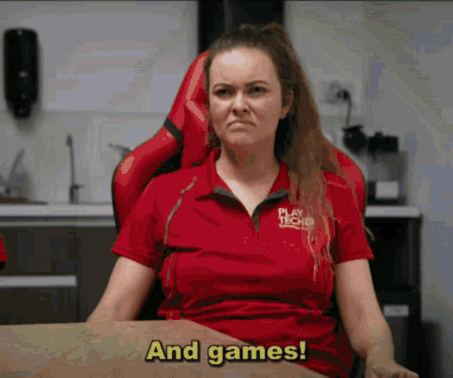 a woman wearing a red shirt that says play tech sits at a table
