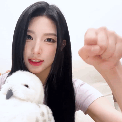 a woman with long black hair is holding a stuffed animal in her arms