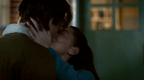a man and a woman are kissing in front of a window that says ' tc ' on it