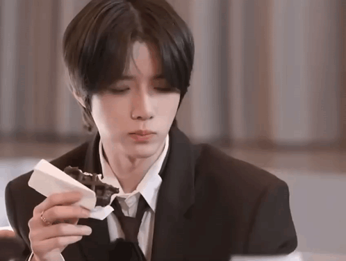 a man in a suit and tie eating a piece of chocolate