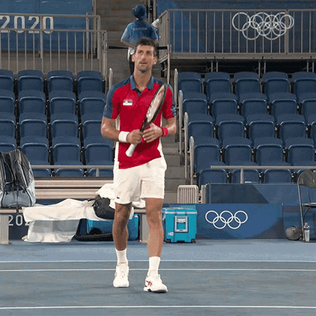 a man holding a tennis racquet in front of a sign that says 2020 on it