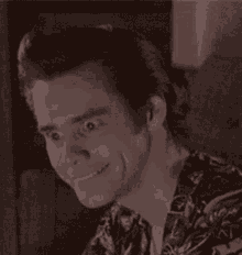 a close up of a man making a funny face while wearing a floral shirt .
