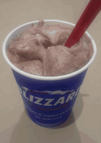 a cup of blizzard ice cream has a red spoon in it