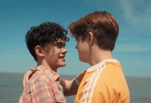 two young men looking at each other with one wearing an orange adidas shirt