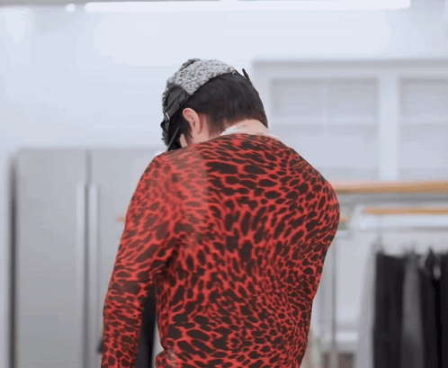 a man in a red leopard print sweater is standing in a room