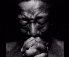 A dark grayscale figure clasps hands in prayer while “PLEASE” repeats across the frame.