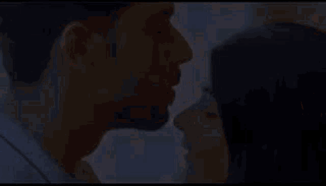 a man and a woman are kissing each other in a close up of their faces .