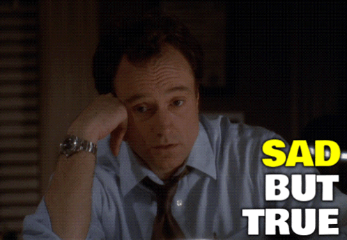 a man in a blue shirt and tie is sitting at a desk with the words sad but true above him