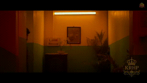 a man is walking down a hallway in a dark room with a picture on the wall .
