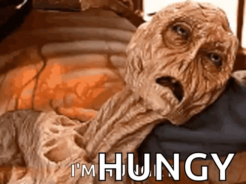 A wrinkled alien-like creature looks distressed with “I'M HUNGRY.”
