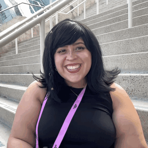 a woman wearing a black shirt and a purple lanyard with the letter j on it smiles for the camera