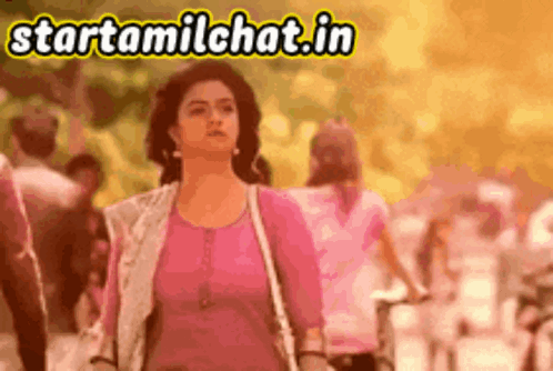 a woman in a pink shirt is walking down a street with a sign that says starttamilchat.in