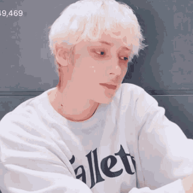 a young man with blonde hair is wearing a white sweatshirt with the word ballet on it .