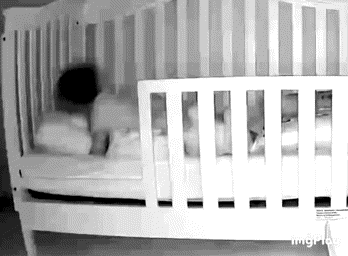 a baby is sleeping in a white crib with a black and white photo .