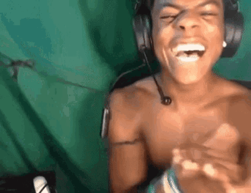 IShowSpeed laughs exuberantly and claps while wearing headphones.