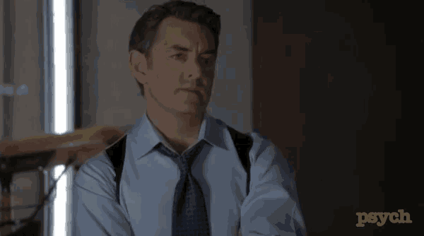 a man in a blue shirt and tie is standing in front of a wall that says psych