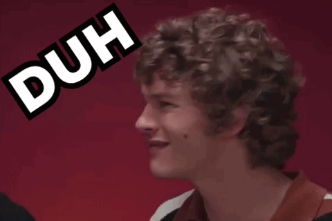 A curly-haired man turns and smiles awkwardly beside a bold “DUH” graphic.