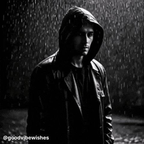a man wearing a hooded jacket stands in the rain