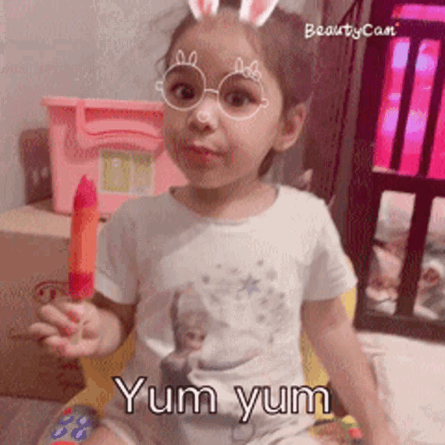 a little girl wearing glasses and bunny ears is holding a popsicle and the words yum yum are below her