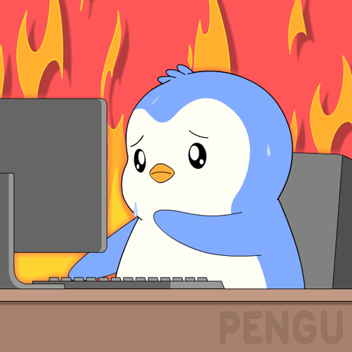 A blue cartoon penguin sweats at a computer while flames rise behind it.