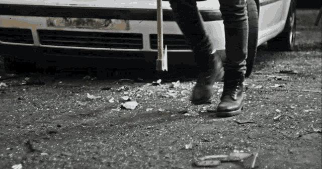a person standing next to a car with a hammer in their hand