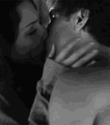 A couple kiss closely in a dark black-and-white scene.