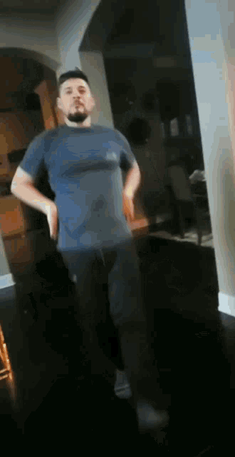 a man in a blue shirt is standing in a living room .