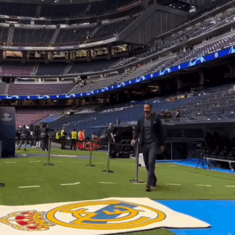 a man in a suit walks across a soccer field