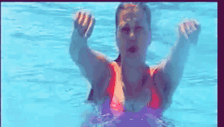 a woman in a red bikini is swimming in a pool with her hands in the air .