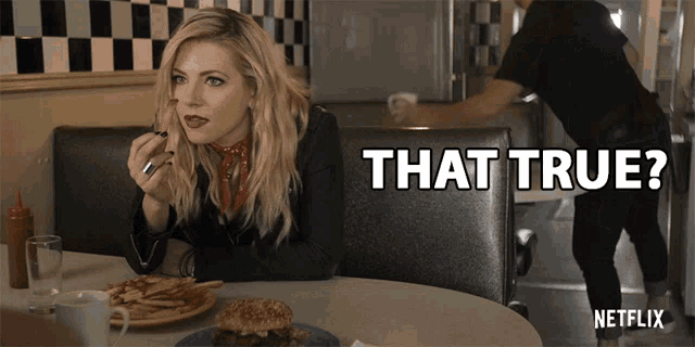 a woman is sitting at a table with a plate of food and a sign that says " that true "