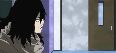 a man with long black hair and a scarf is standing in a hallway next to a door .
