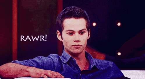 a man in a blue shirt is sitting on a couch with the word rawr written on the screen behind him