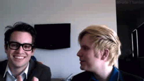 two men are sitting next to each other and smiling .