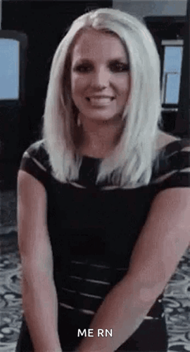 Britney Spears sits with an uneasy smile and looks toward the camera.