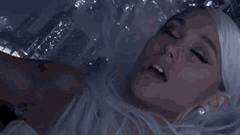 ariana grande is wearing a white wig and holding a microphone .