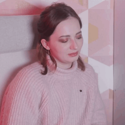 a woman wearing a pink sweater and white earbuds