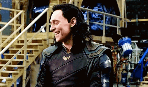 loki ragnarok is smiling while standing in front of stairs in a room .