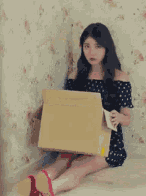 Woman sitting on the floor holds a blank sign with an uneasy expression.