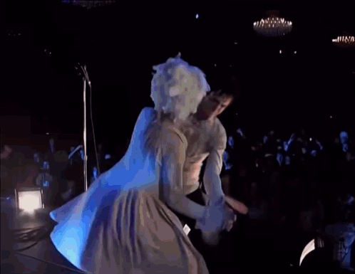 a woman in a white dress is dancing on a stage in front of a sign that says sonic