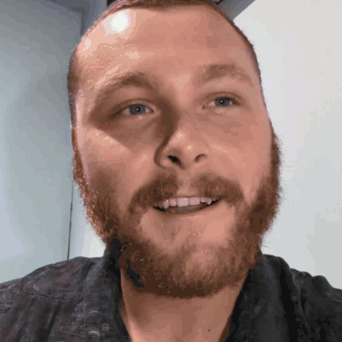 a man with a beard and a black shirt smiles