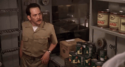 a man in a military uniform says " what the hell are you doing " in front of a shelf full of cans