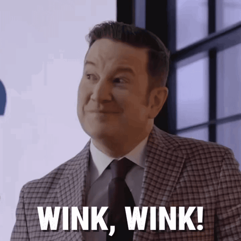Ken Reid smiles and winks in a studio setting with “WINK WINK!” text.