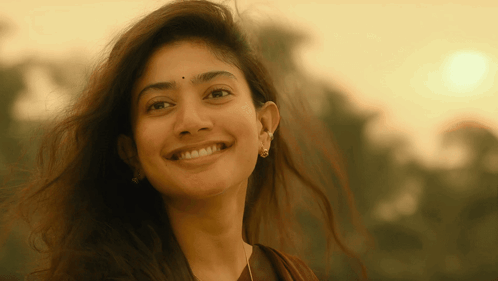 Sai Pallavi smiles warmly outdoors in golden light.