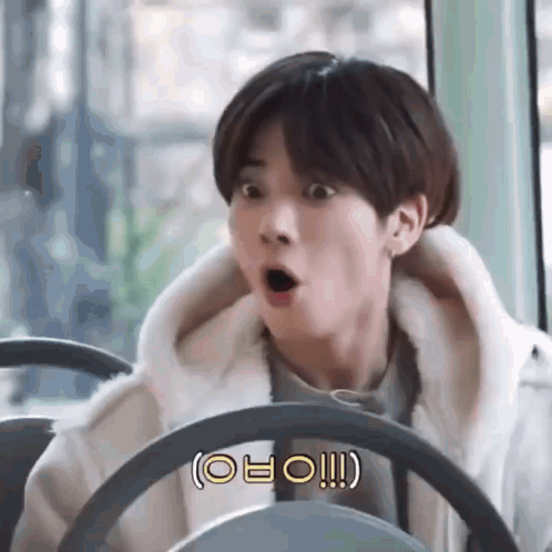 a young man is sitting in a bus with his mouth open .