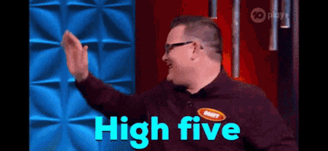 A man reaches for a high five on a brightly lit game-show set.