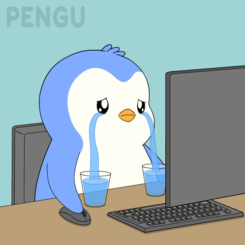A blue penguin cries at a computer desk.