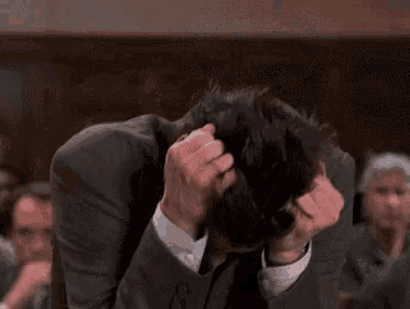 Jim Carrey hunches over with his hands gripping his head.